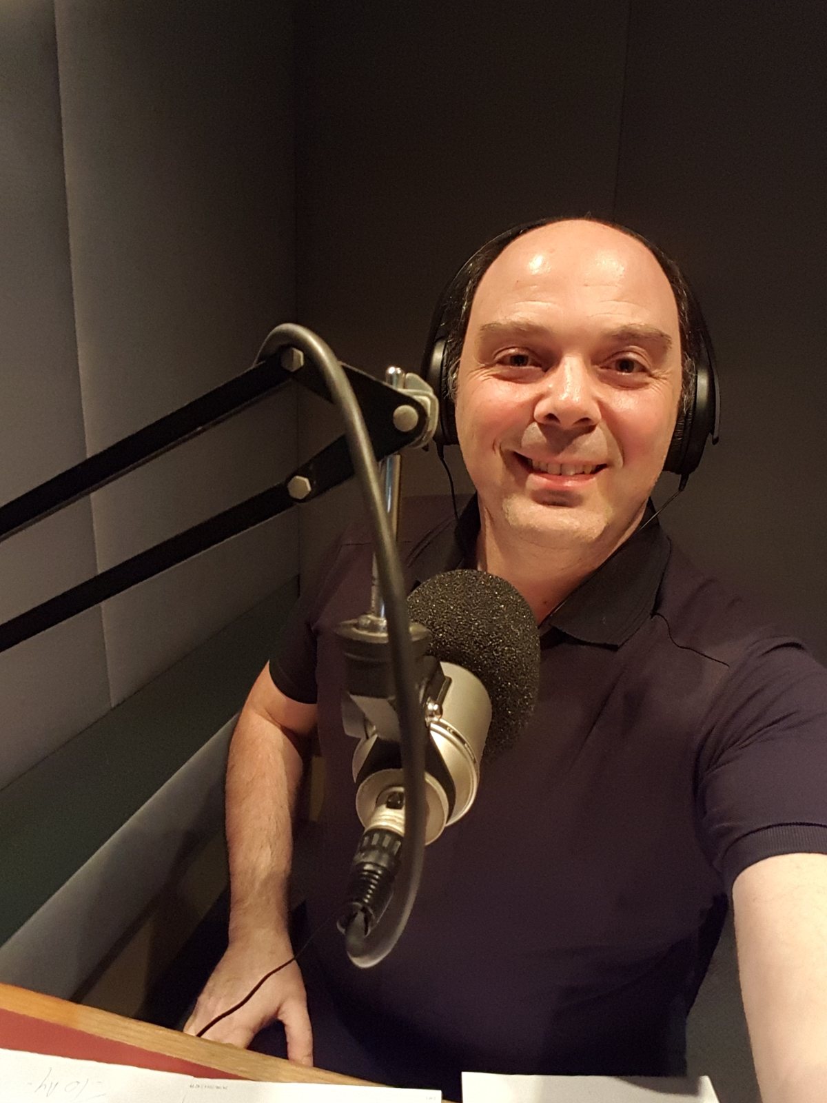 Morris Misel in a radio studio with headphones and a microphone, smiling