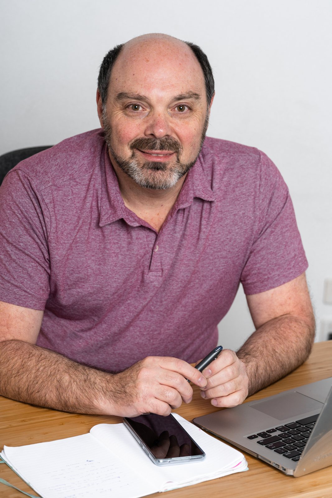Morris Misel at his desk with a notebook and laptop, smiling